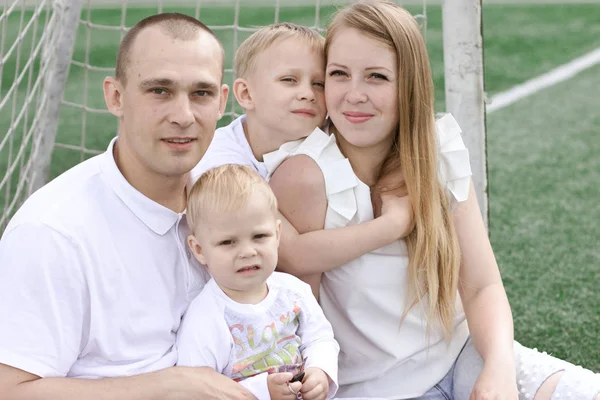 Eine vierköpfige Familie auf einem Fußballplatz. strahlend sonniger Sommertag. — Stockfoto