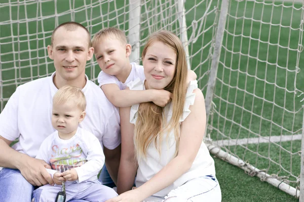 Uma família de quatro num campo de futebol. Brilhante dia de verão ensolarado . — Fotografia de Stock