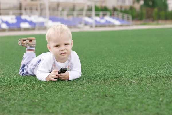 Ein kleiner Junge liegt auf dem Fußballplatz. — Stockfoto