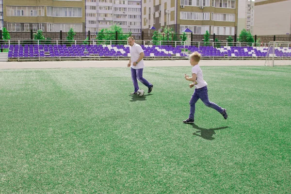 Baba oğlu futbol oynarken yürür. 