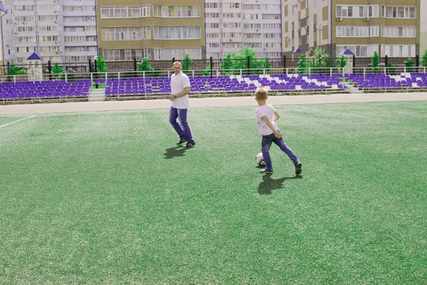 Baba oğlu futbol oynarken yürür. 