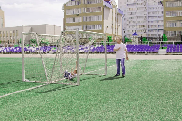 Baba oğlu futbol oynarken yürür. 