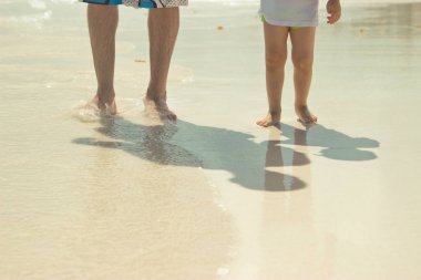 Baba ve oğul plaj boyunca yürüyor. Yakın çekim bacaklar. Beach Punta Cana, Dominik Cumhuriyeti için.