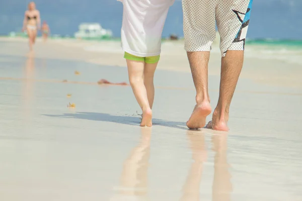 Dad and son are walking along the beach. Close-up of legs. Beach in Punta Cana, Dominican Republic.