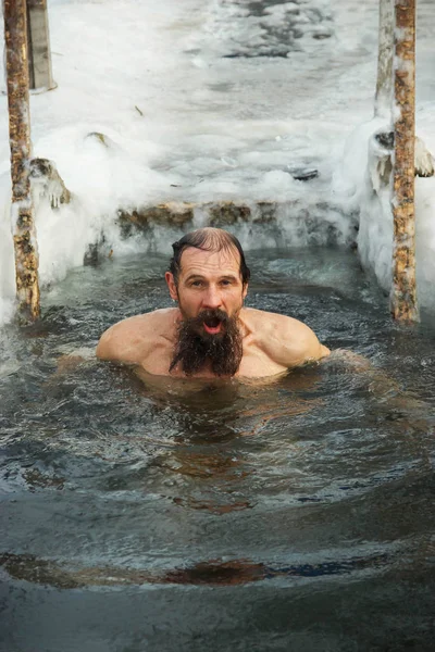 Un homme d'âge moyen est plongé dans un trou de glace . — Photo