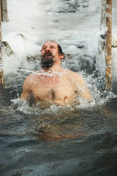 Un homme d'âge moyen est plongé dans un trou de glace . — Photo