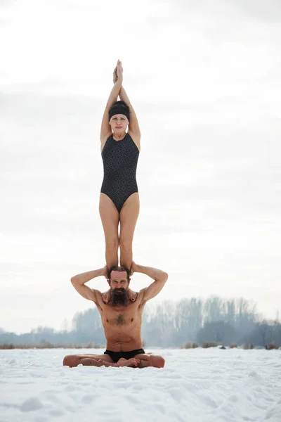 Мужчина и женщина средних лет практикуют йогу на замерзшей реке . — стоковое фото