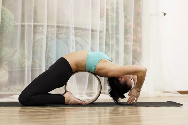 Orta yaşlı bir kadın ile bir tekerlek yoga yapar.
