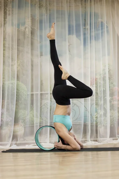 Orta yaşlı bir kadın ile bir tekerlek yoga yapar.