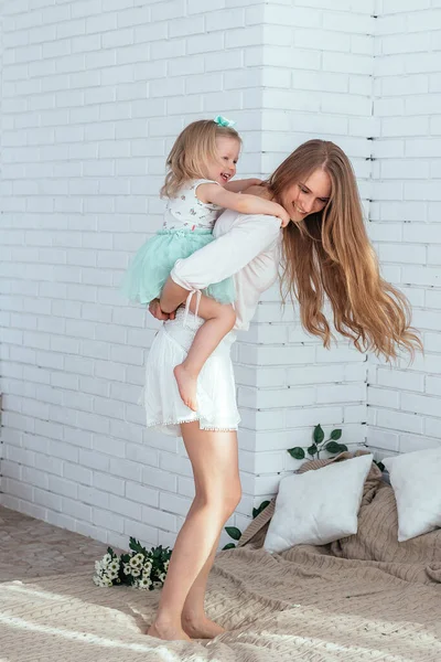 Mom and daughter have fun together. Mom rides her daughter on her back.