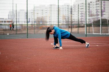 Genç bir kadın oyun parkında spor yapıyor. Rusya 'da ilkbahar başlarında.
