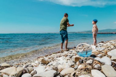 Sahildeki baba-oğul oyununun gözlüklerindeki yansıma. Ortak eğlence ve seyahat konsepti. Konum - Gelendzhik, Rusya.