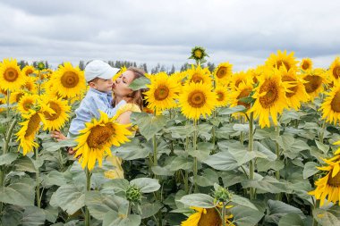 Anne ve oğlu ayçiçeği tarlasında vakit geçiriyorlar. Kırsal alan, Rusya.