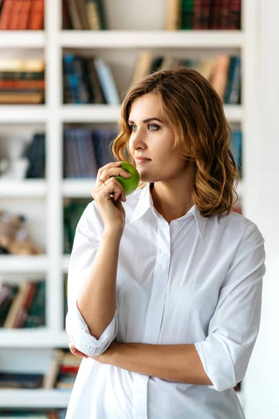 Jonge vrouw met groene apple girosaldi permanent in de bibliotheek — Stockfoto