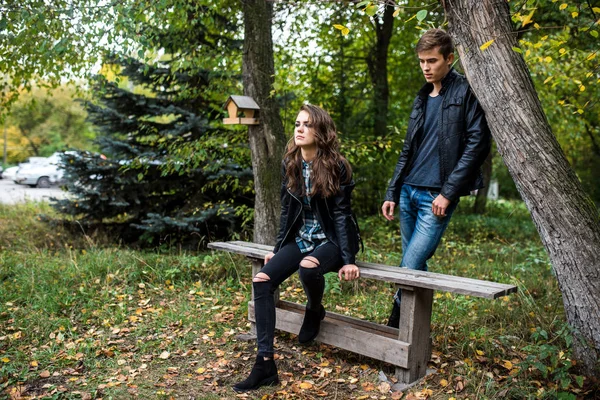 Beautiful woman  sits on a bench behind her man — Stock Photo, Image