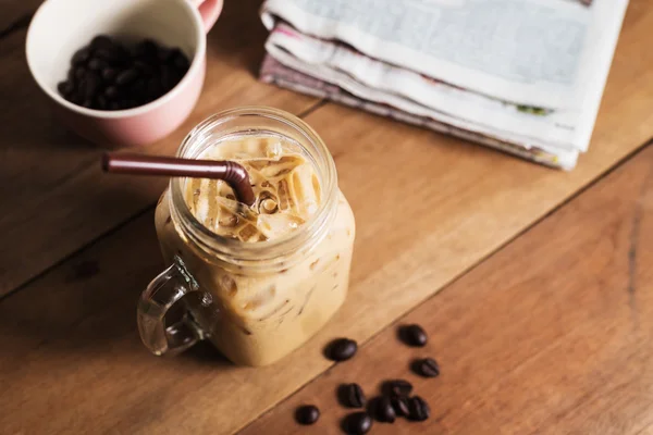 Ijs koffie met melk en krant op tafel — Stockfoto