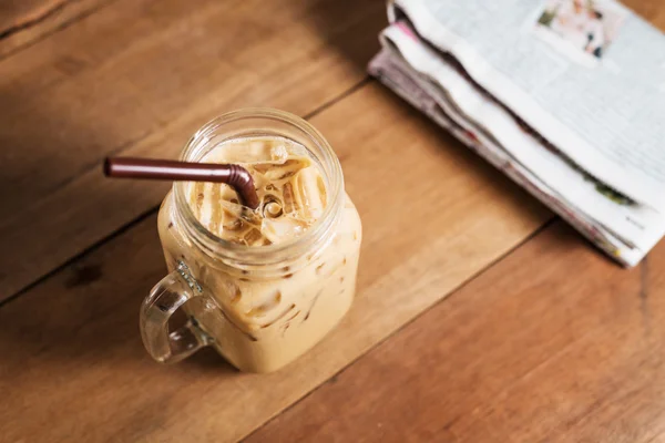 Ijs koffie met melk en krant op tafel — Stockfoto