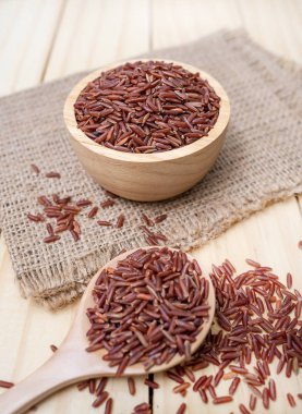 Ahşap arka plan üzerinde kırmızı kasede pirinç berry