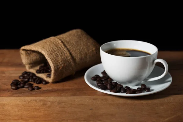 Coffee cup with coffee bean on brown wooden table — Stock Photo, Image