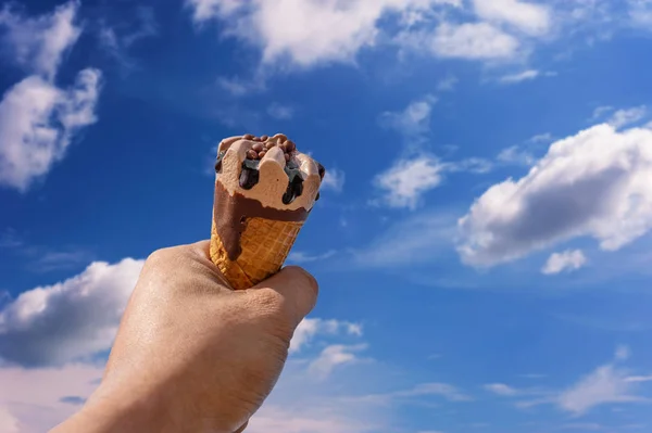 Main avec crème glacée sur fond bleu ciel flou nature — Photo