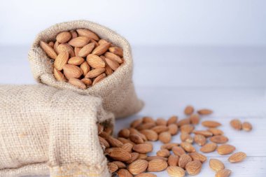 Bulanık beyaz masa üzerinde bez torba badem