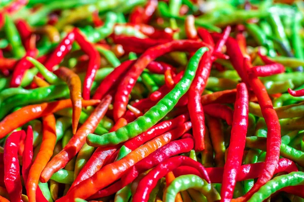 Green pepper on red peppers blurred background — Stock Photo, Image