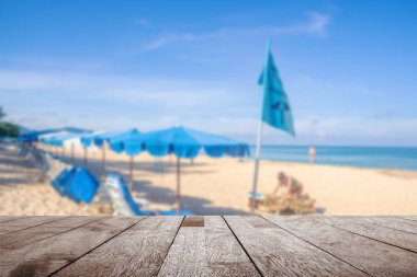 Ahşap masa, bulanık şemsiye ve bazı insanlar dinleniyor.