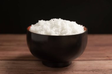 Tahta arka planda siyah kasede beyaz pirinç.