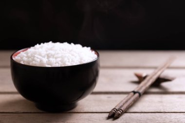 Tahta arka planda siyah kasede beyaz pirinç.
