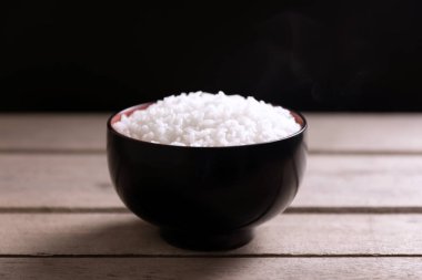 Tahta arka planda siyah kasede beyaz pirinç.