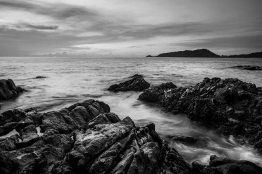 Deniz batımı ya da gün doğumu bulutlarla dolu gökyüzü ve alacakaranlık, siyah-beyaz ve tek renkli güneş ışığı