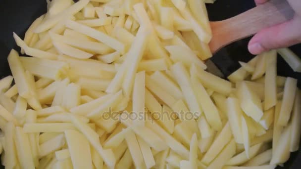 Vrouwelijke handen draai frietjes met een houten spatel. Huis keuken. — Stockvideo