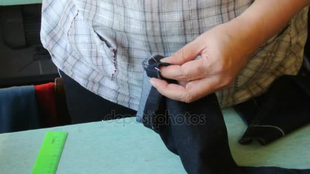 Home seamstress makes preliminary manual suture. Female hands sheathe jeans. — Stock Video