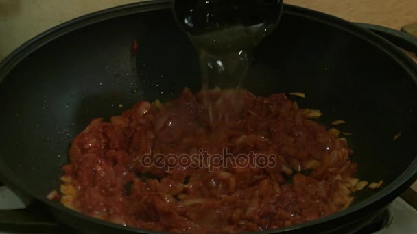 Le mani maschili aggiungono acqua alle cipolle con concentrato di pomodoro nella padella. Cucina russa . — Video Stock