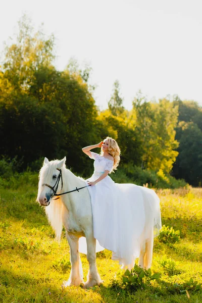 Novia montando un caballo en el fondo de un atardecer de verano — Foto de Stock