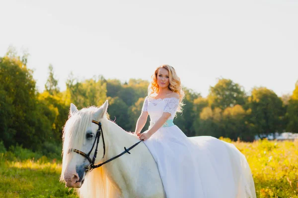 Retrato de una novia a caballo sobre el fondo de una puesta de sol de verano — Foto de Stock