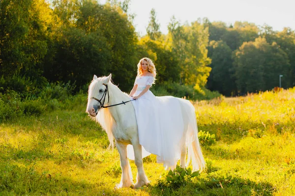 Novia montando un caballo en el fondo de un atardecer de verano — Foto de Stock