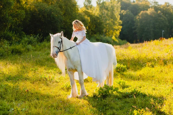 Novia montando un caballo en el fondo de un atardecer de verano — Foto de Stock