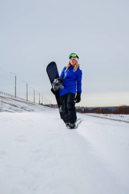 Genç kadın ve onun snowboard kar kaplı dağın gün batımında