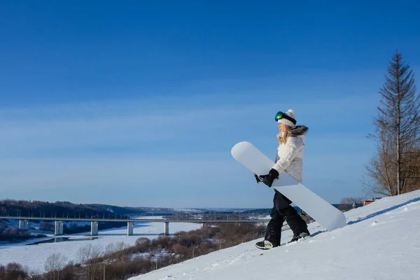 Jonge vrouw en haar witte snowboard op besneeuwde berghelling — Stockfoto