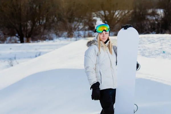 Mujer joven y su snowboard blanco en la ladera de la montaña cubierta de nieve — Foto de Stock