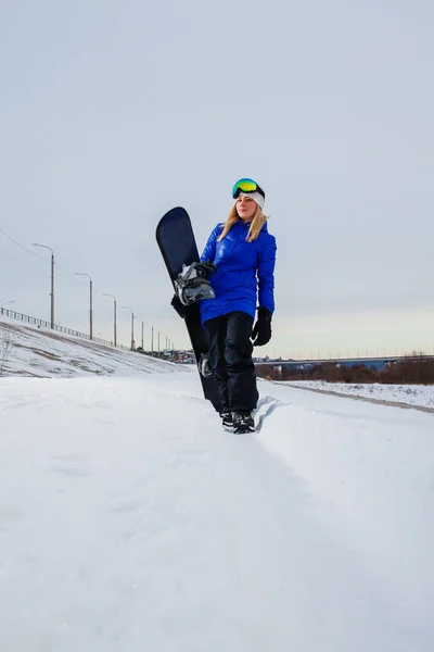Giovane donna e il suo snowboard sulla montagna innevata al tramonto — Foto Stock