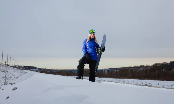 Giovane donna e il suo snowboard sulla montagna innevata al tramonto — Foto Stock