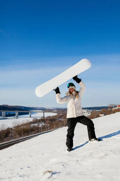 Mujer joven mostrando su tabla de snowboard como un marco blanco —  Fotos de Stock