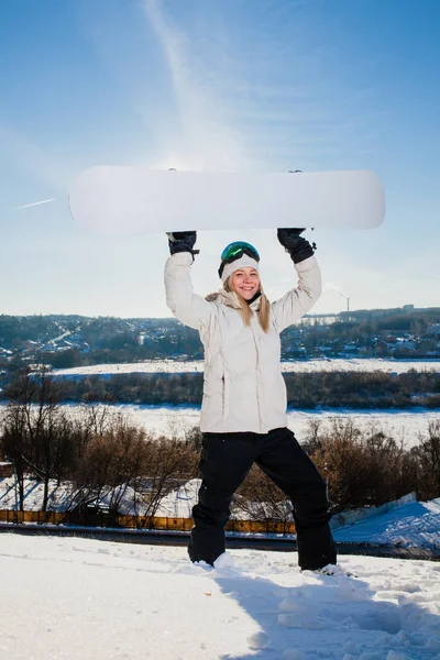 Ung kvinna visar sin snowboard som en vit ram — Stockfoto