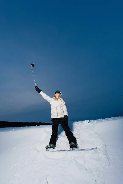 通过她的手机拍摄自拍照的滑雪板的年轻女子 — 图库照片
