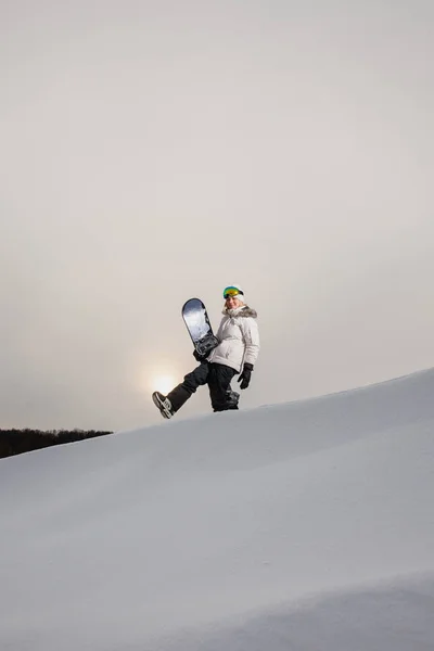 Mujer joven y su tabla de snowboard en la montaña cubierta de nieve — Foto de Stock