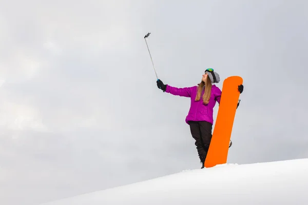 Молода жінка зі сноубордом знімає селфі на мобільному телефоні — стокове фото