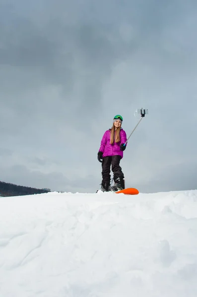 Junge Frau mit dem Snowboard schießt ein Selfie mit ihrem Handy — Stockfoto