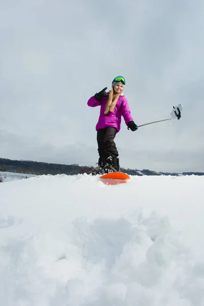 Junge Frau mit dem Snowboard schießt ein Selfie mit ihrem Handy — Stockfoto